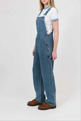 Person wearing blue denim overalls on a white background