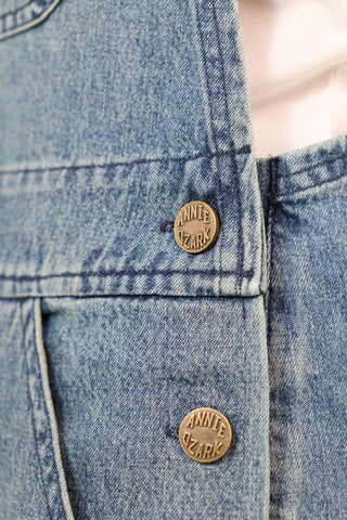 Close-up of a blue denim jacket with brand buttons.