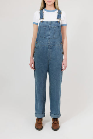 Person wearing blue denim overalls on a white background