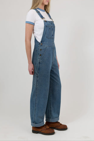 Person wearing blue denim overalls on a white background