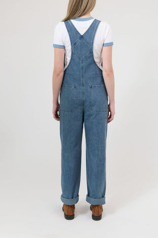 Person wearing blue denim overalls on a white background