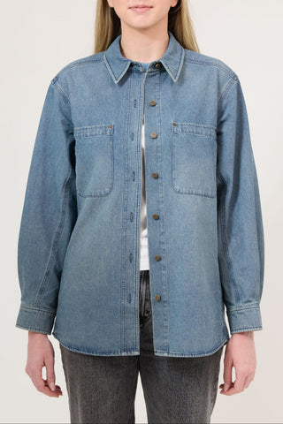 Person wearing a blue denim shirt on a plain background
