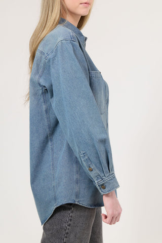 Person wearing a blue denim shirt on a plain background