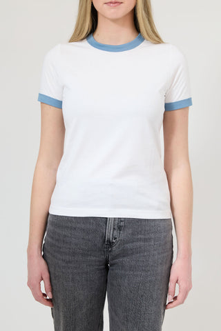 Person wearing a white t-shirt with blue trim and gray jeans on a plain background