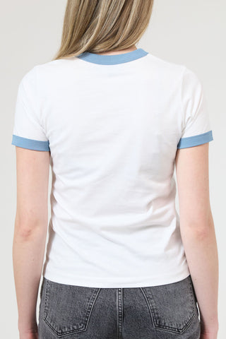 Person wearing a white t-shirt with blue trim and gray jeans on a plain background