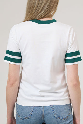 Person wearing a white t-shirt with green sleeves and blue jeans on a plain background