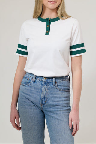 Woman wearing a white and green striped shirt with blue jeans on a plain background