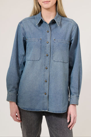 Denim shirt worn by a person on a plain background