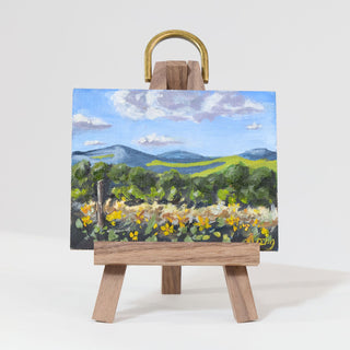 Miniature landscape painting on a small easel with a white background