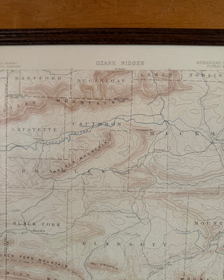 A vintage topographic map of the Ozark Ridges, featuring hand-drawn contour lines in brown and blue on aged beige paper, with a dark wood frame visible at the top.