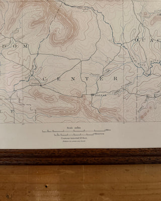 An antique topographical map of 'Center' showing contour lines, roads, and place names like Dallas and Ottawa, mounted on a wooden board above a wooden surface.