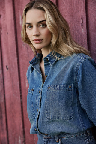 Woman wearing a blue denim shirt against a red wooden background