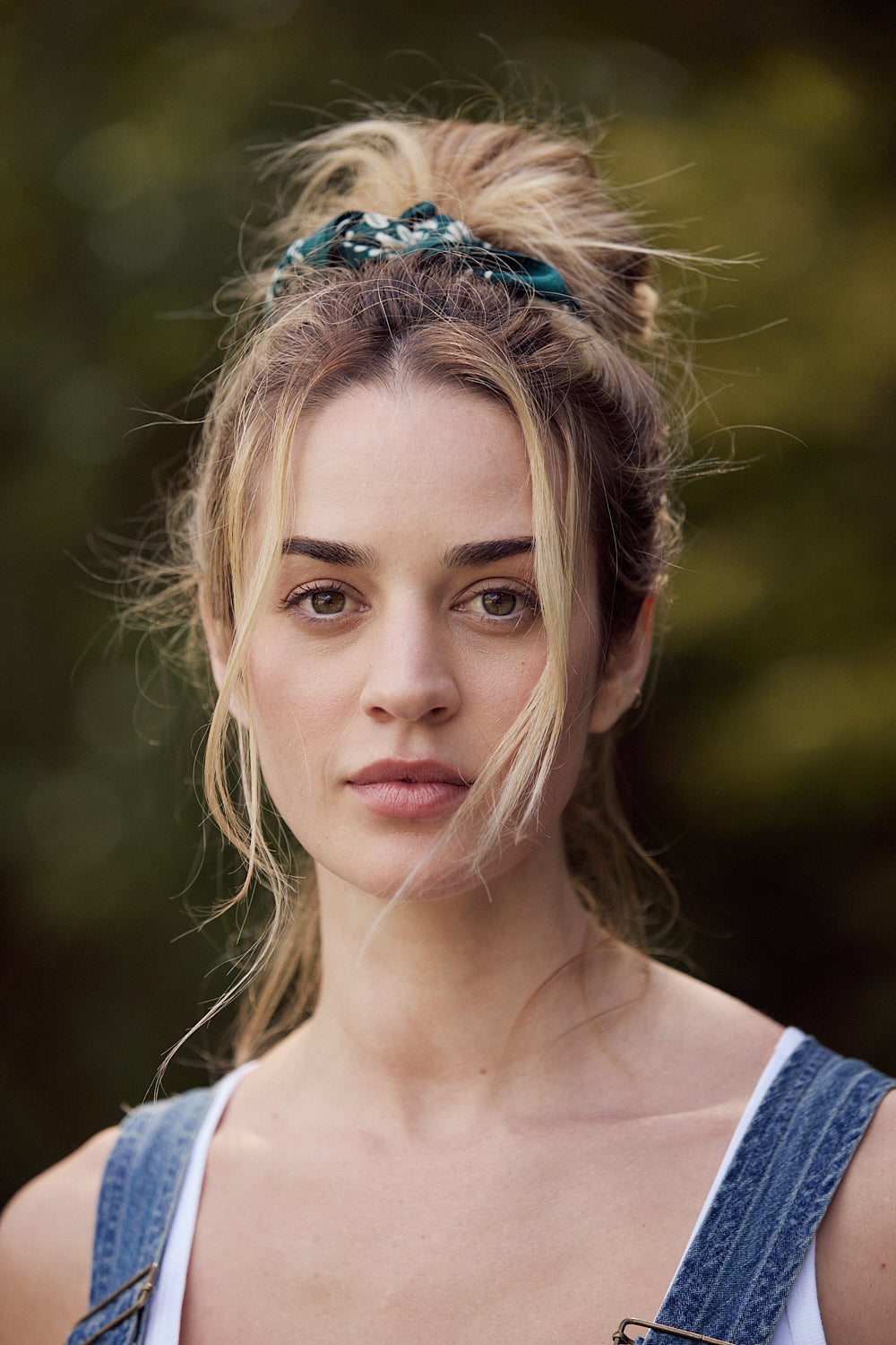 Woman with a bun hairstyle wearing a headband against a blurred natural background