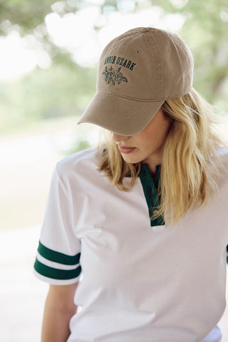 Person wearing a beige cap with text and graphics, outdoors